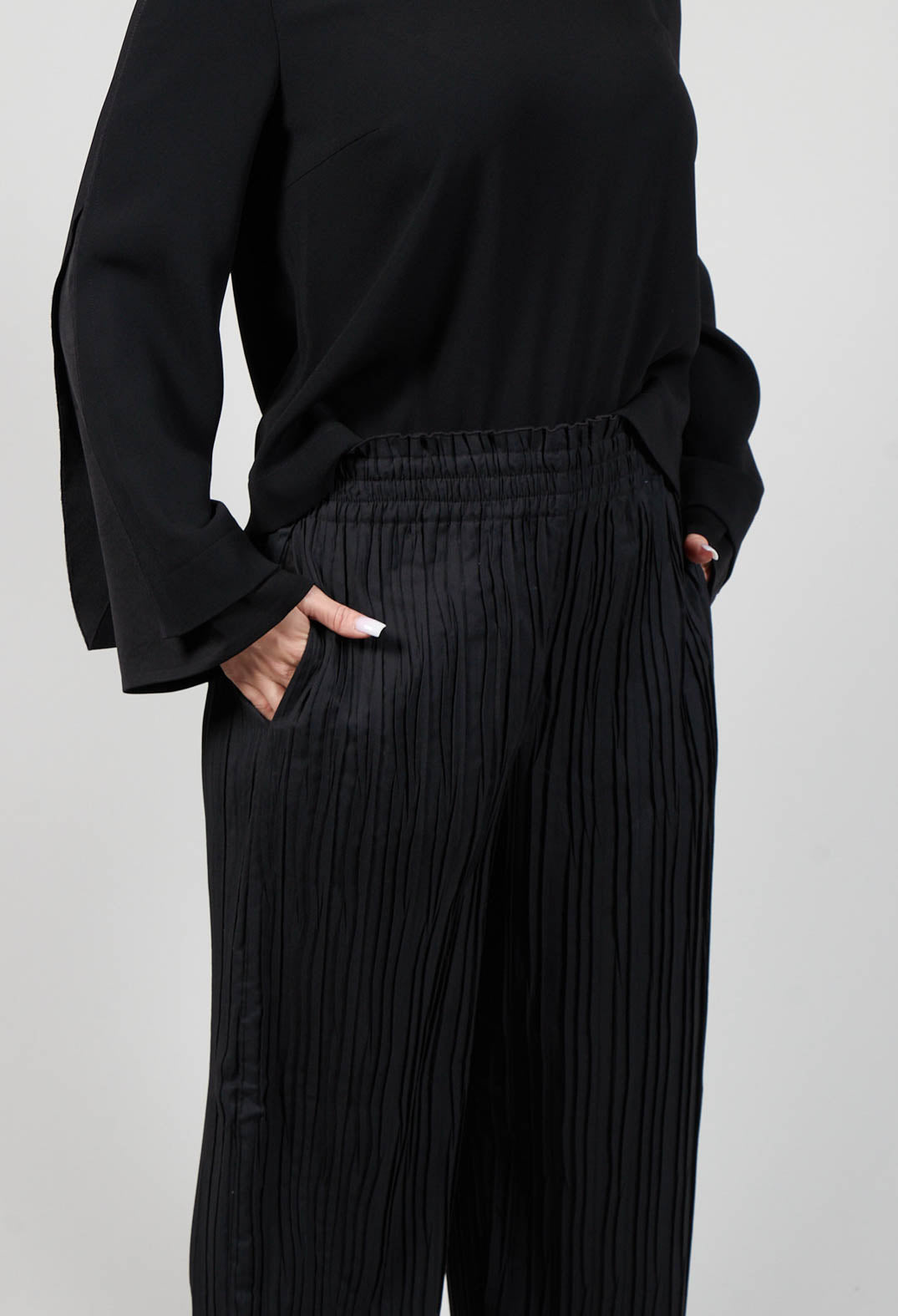 close up of ladies black wide leg trousers in a shiny fabric with side pockets