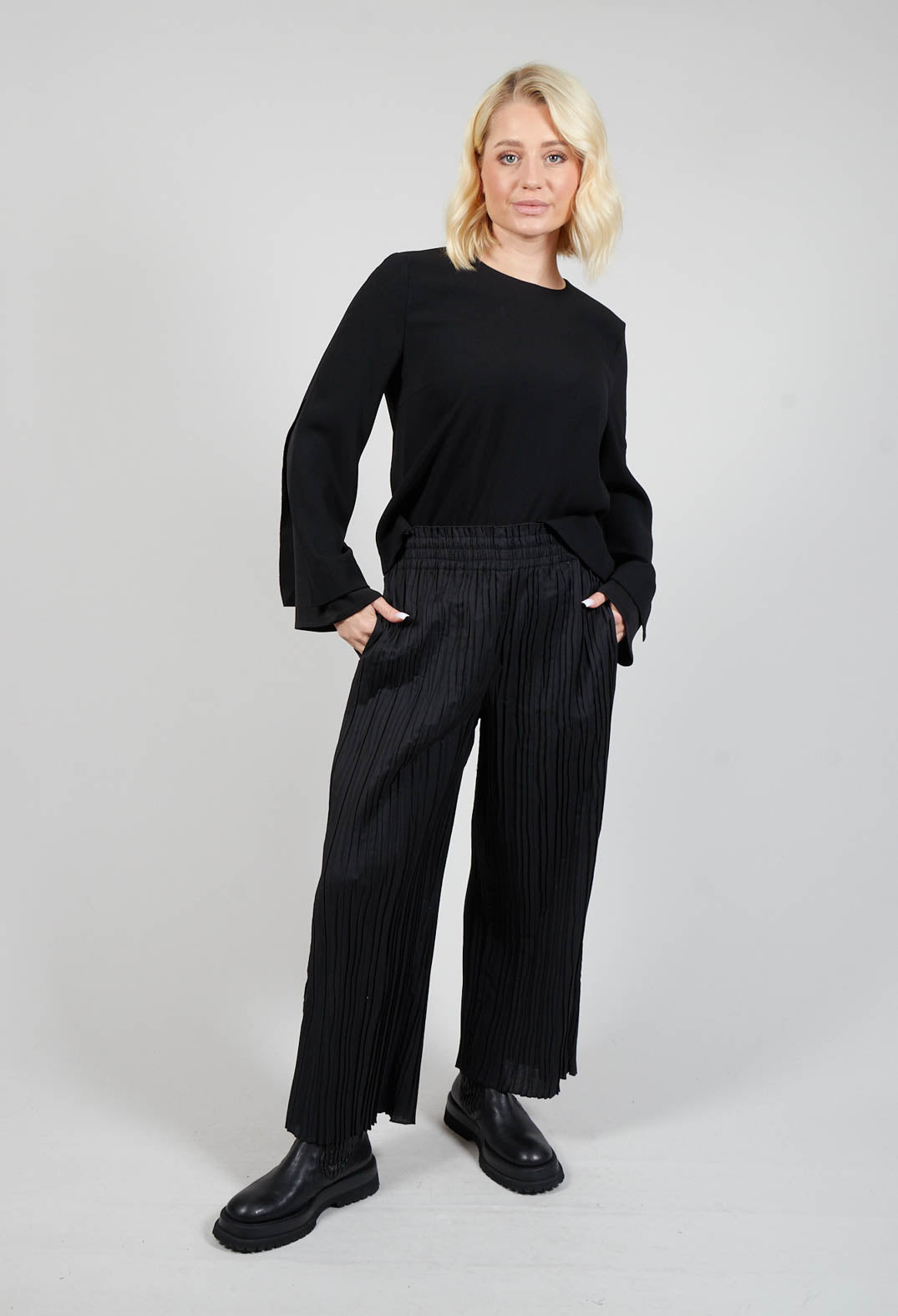 long shot of lady wearing wide leg black trousers with a black top and chunky boots