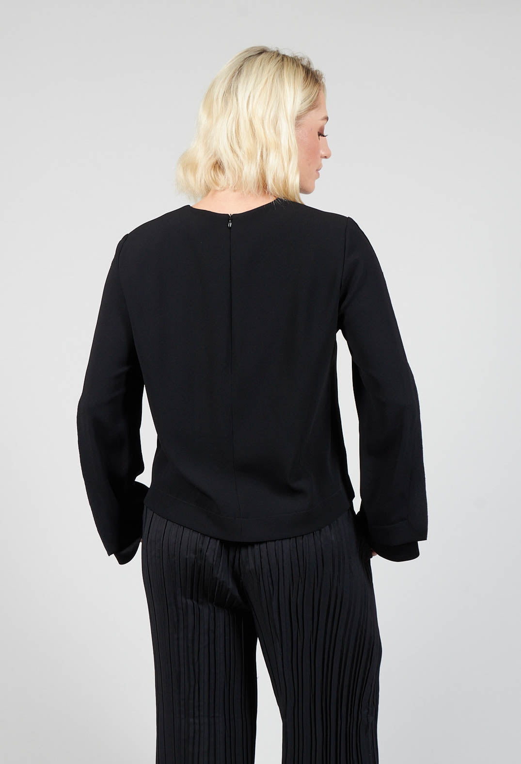 behind shot of lady wearing a long sleeve black blouse and wide leg trousers