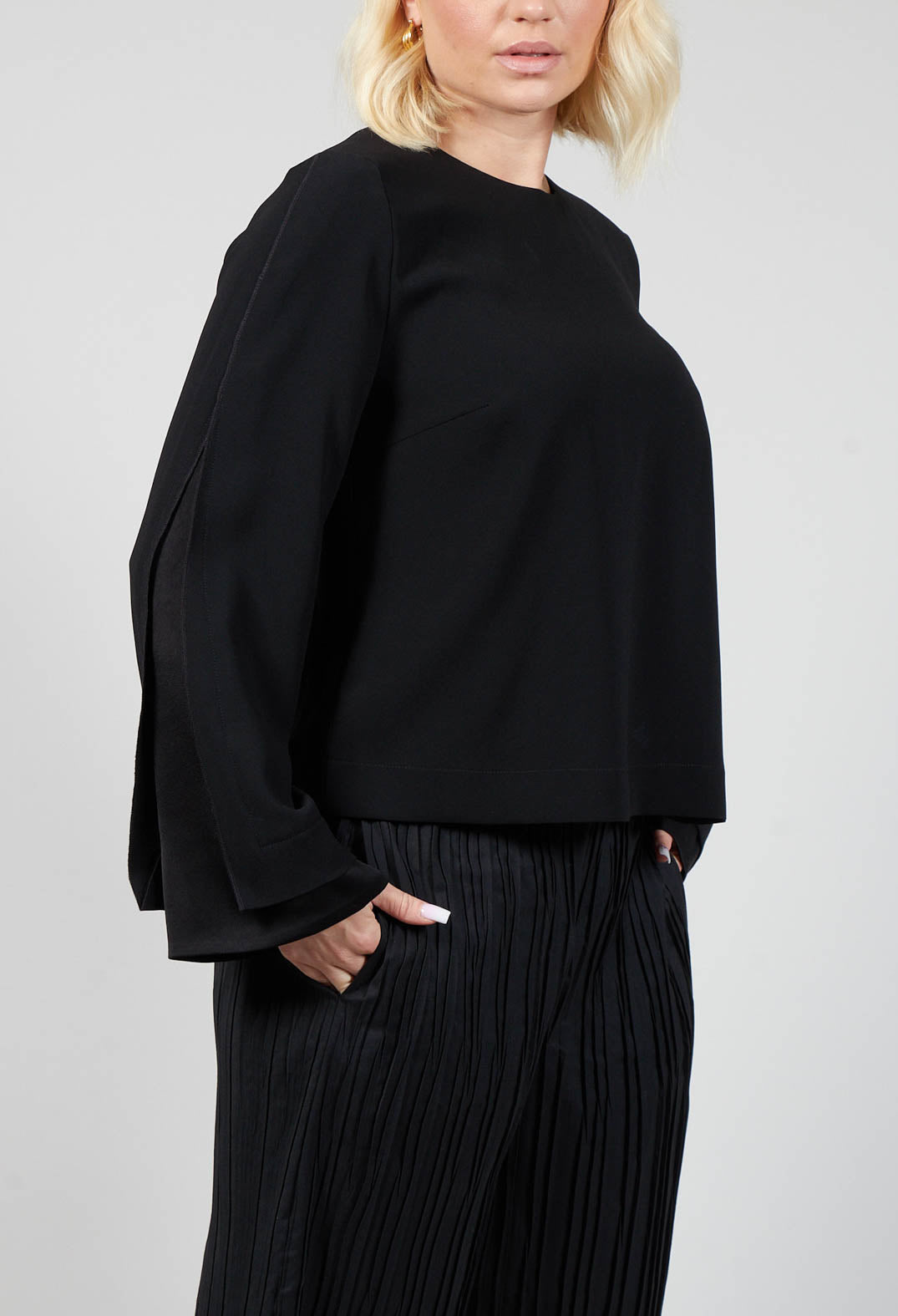 lady wearing a smart long sleeve black blouse with pleated trousers