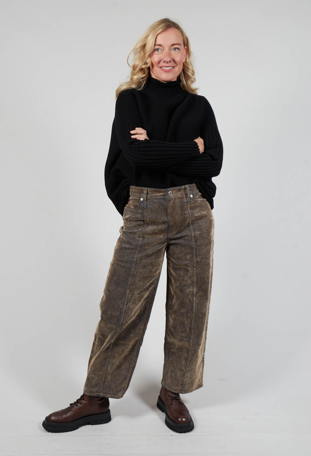 smiling lady wearing a black jumper and brown wide leg trousers and chunky boots