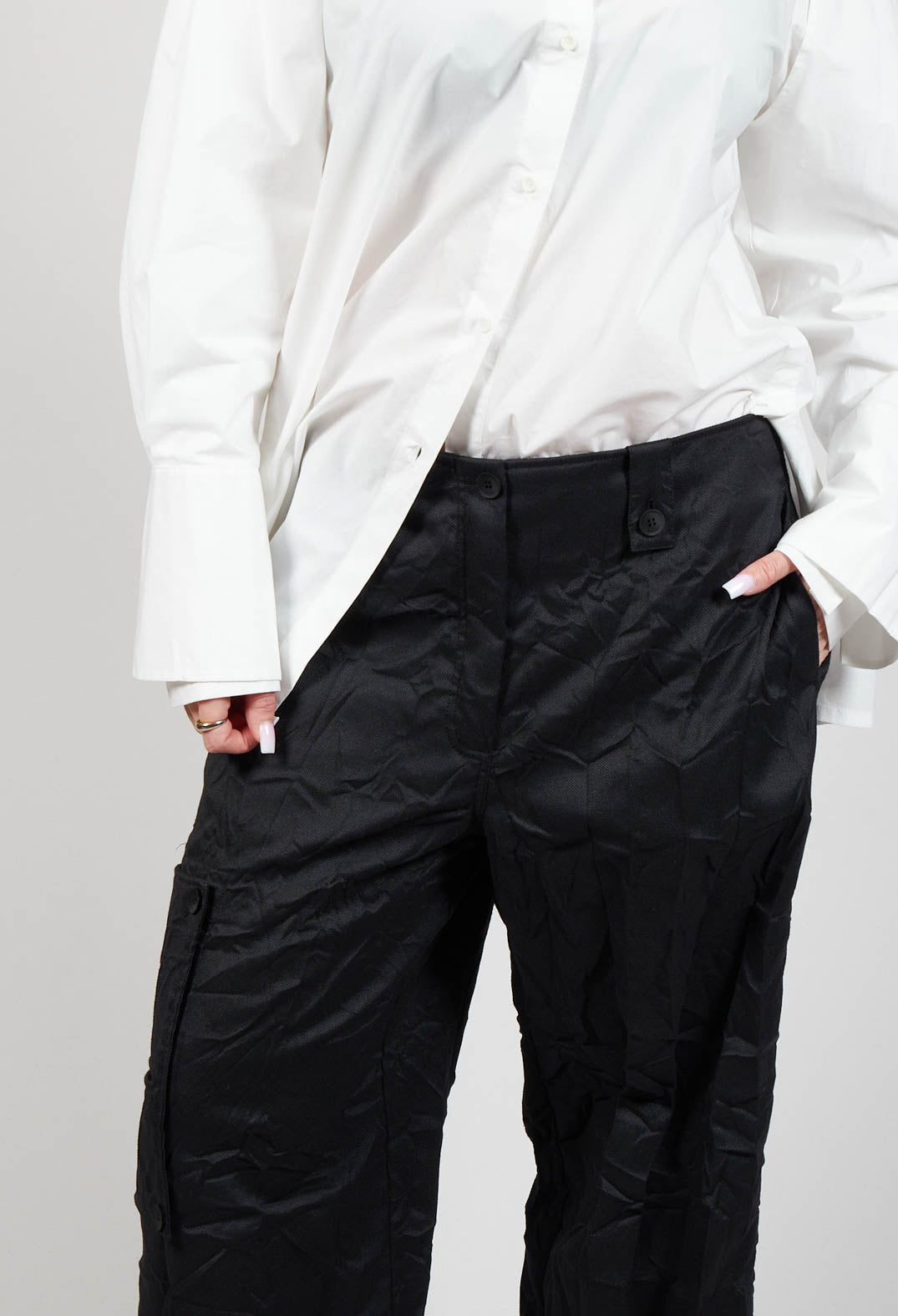 close up shot of black peka trousers which have side pockets, belt loops and button fastening